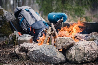 backpack and metal kettle on a campfire in the forest