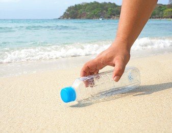 hand was holding the clear plastic water bottle lying on sandy beach,concept,concept garbage collection on beach