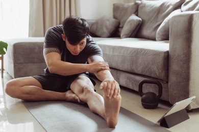 fit man in sportwear streching after exercise at home. young asian man streching before workout.