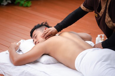 asian man enjoy a massage by the resort's pool. 