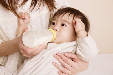 baby drinking milk while being embraced by mother