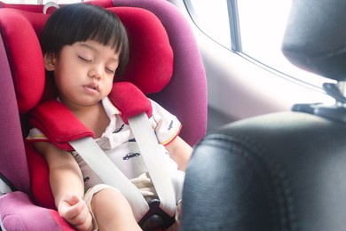 happy asian toddler boy sleeping safety in car seat on travel trip with family. insurance, family and safety of baby in car concept.