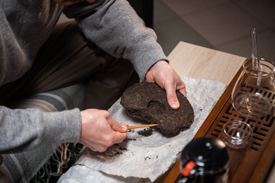 shot without a face. close-up of the master's hands picking a tea cake with a needle for a tea ceremony or chinese tea tasting.