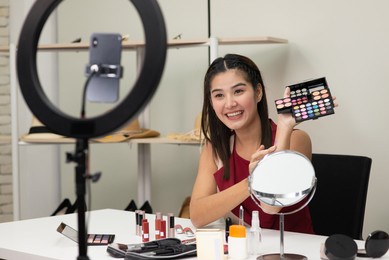 beautiful asian woman beauty makeup artist vlogger advertise beauty cosmetic product on social media live streaming on smartphone. online shopping business advertising by blogger or influencer concept