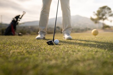 golfer getting ready to hit the ball near the golf club bag.