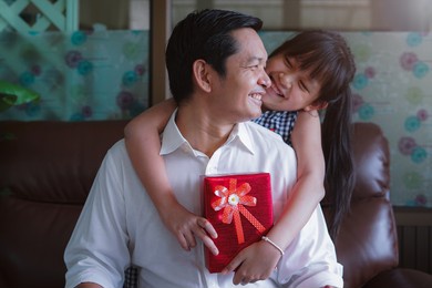 asian little daughter congratulating dad and giving him gift box with smiling and hugging.concept of happy father's day