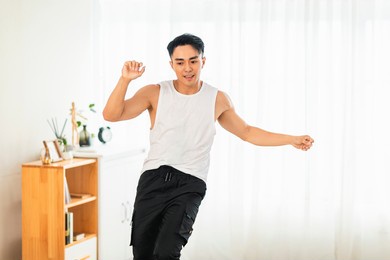 happy asian young man doing exercises and dancing at home
