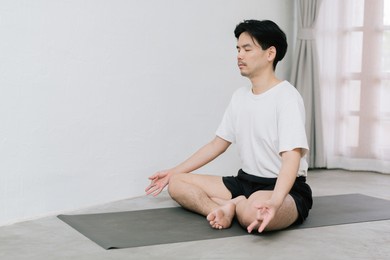 asian young man doing yoga at home