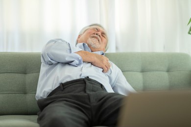 emergency of asian elderly senior man sudden heart attack so pain on chest and illness with diabetes symptoms on sofa due working alone and need urgently help at home,elderly care concept