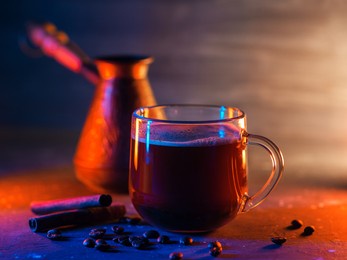 glass cup of hot freshly brewed coffee , dark background with colored lighting. turkish coffee, cezva