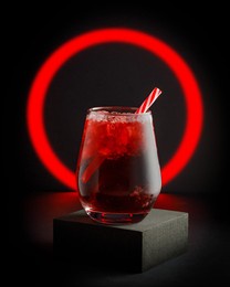 glass of red soft drink on black background with red neon circle