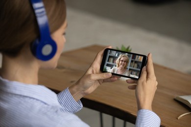 teen female listener in headset get online consultation of elderly woman coach watch virtual training at web platform on cell. young lady in earphones take break from work call mother by video link
