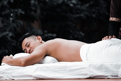asian man enjoy a massage by the resort's pool. 