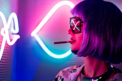 beautiful girl in a violet wig is drinking smoking. photography in a futuristic neon blue and violet colors, might be a concept for future, urban, cyberpunk etc