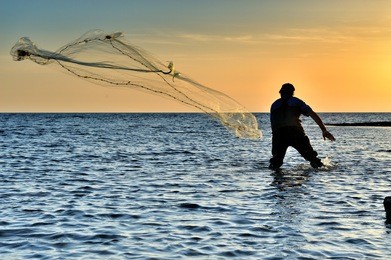 throwing fishing net during sunset
