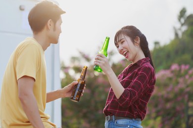 travel asian couple having fun drinking beers standing in front of vintage camper mini van. happy people enjoying drink and camping by the nature. concept of leisure vacation lifestyle.