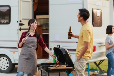 happy diversity ethnic friends drinking beers at camping barbecue picnic by the nature. young adult people having fun and laughing together - travel, vacation and friendship concept.