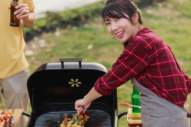 happy diversity ethnic friends drinking beers at camping barbecue picnic by the nature. young adult people having fun and laughing together - travel, vacation and friendship concept.