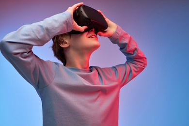 shocked young guy in virtual reality helmet, looking into vr glasses screen. young caucasian boy is surprised by reality vr helmet. isolated in studio, portrait. modern technologies concept