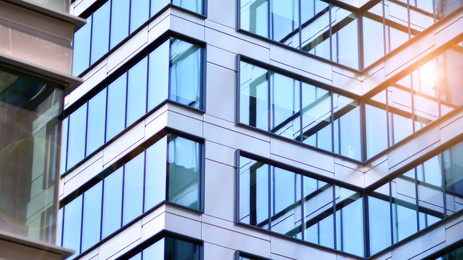 modern architecture with sun ray. glass and steel facade on a bright sunny day with sunbeams on the blue sky. economy, finances, business activity concept.