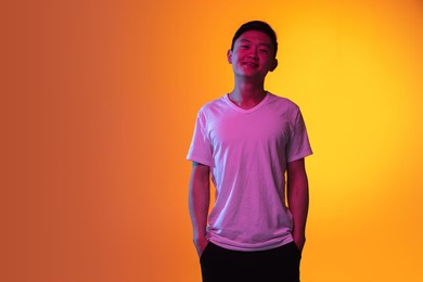 portrait of asian young man isolated over orange yellow background in neon light.