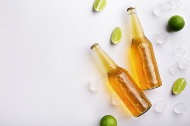 beer advertisement and evening in pub. two full transparent glass bottles with ale without labels, with flowing drops, lie with ice cubes and pieces of lime, on white background, free space