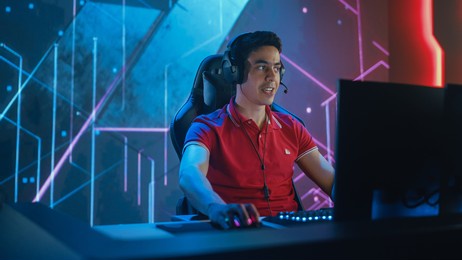 professional esports gamer playing in computer video games. background stylish graphics. online championship tournament streaming event. portrait semi-side view shot
