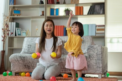happy asian family mother and child daughter are playing colorful balls