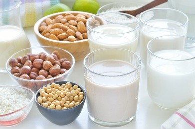 different vegan milks on a table. hazelnut, rice, soya and almond milk. substitute for dairy milk.