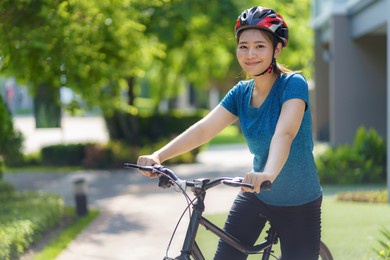 asian woman looking happy while bike ride around her neighborhood for daily health and well being, both physical and mental.