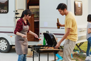 happy diversity ethnic friends drinking beers at camping barbecue picnic by the nature. young adult people having fun and laughing together - travel, vacation and friendship concept.