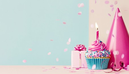 birthday background with pink birthday cupcake and candle, birthday gift and party hat