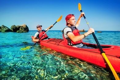 two men paddle a kayak on the sea. kayaking on island