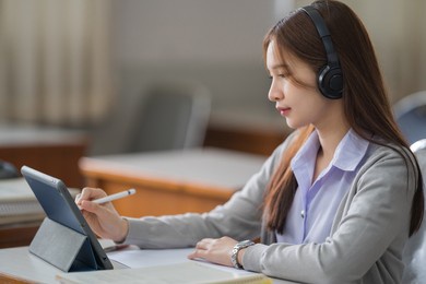 young interactive happy asian teenage girl university student studying and presenting her lesson online via video call on a digital tablet in the classroom alone herself. education stock photo