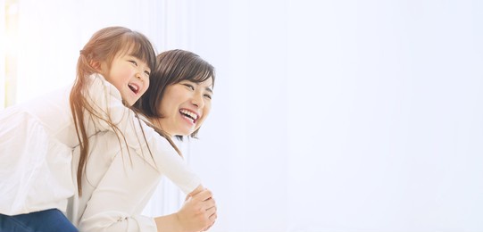 young asian woman piggybacking a little girl.