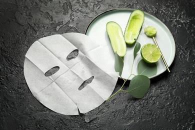 composition with fabric facial mask and cucumber on dark background