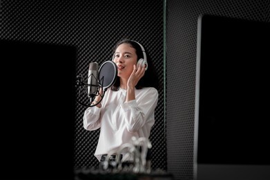 asian female singer with a passion for music and microphone. while playing her guitar in a professional studio. music concept, sound recording concept.