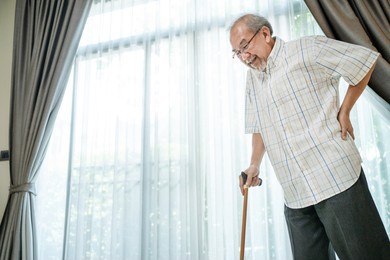 asian senior elderly disabled man patient walking slowly with walker or cane at nursing home care. older handicapped male feeling painful and suffering from backache. medical therapy insurance concept