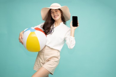 happy asian woman holding mobile phone and beach ball isolated on green background, tourist and holiday trip concept