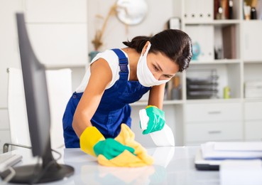 female cleaner working in protective mask productively on task in office