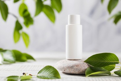 a white tube of cosmetics on a stone among the leaves. the concept of natural plant cosmetics. mockup.