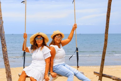 portrait of twins asian young women at beautiful beach. travel on vacation in summer season. enjoy with lovely family holidays in tropical island.
