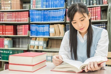 asian student reading book in library at university