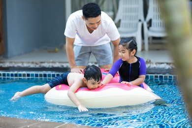 happy asian family vacation. young asian father with son and daughter enjoy by swimming pool at the hotel.