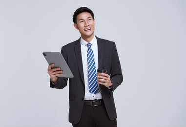 handsome and friendly face asian businessman smile in formal suit his using tablet on white background studio shot.