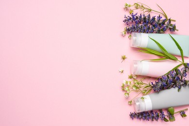 cosmetic tubes on pink background with wild flowers and plants. natural organic cosmetics