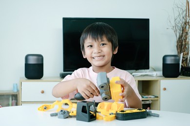 cute asian boy playing and assembling a toy truck at home.
