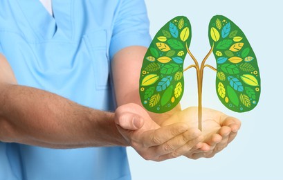 doctor holding drawing of green tree in shape of human lungs on light background