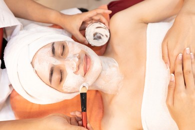 young woman with facial mask at beauty spa salon