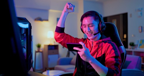 asian man have live stream and win mobile game on the smartphone with raising arm at home